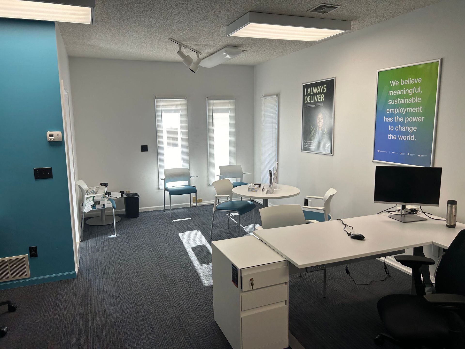 A room with a desk and chairs and a poster on the wall