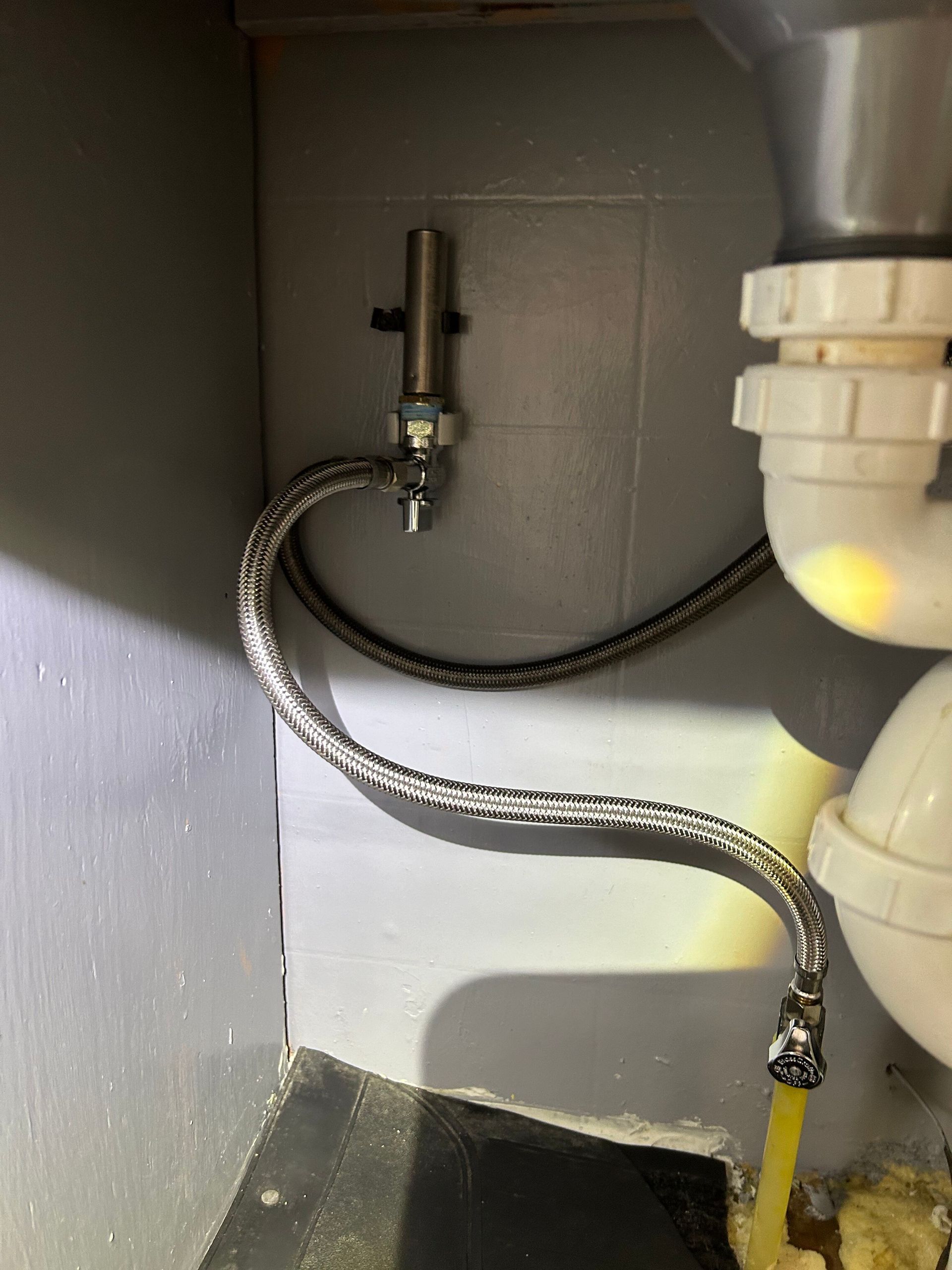 A close up of a sink with a hose attached to it.