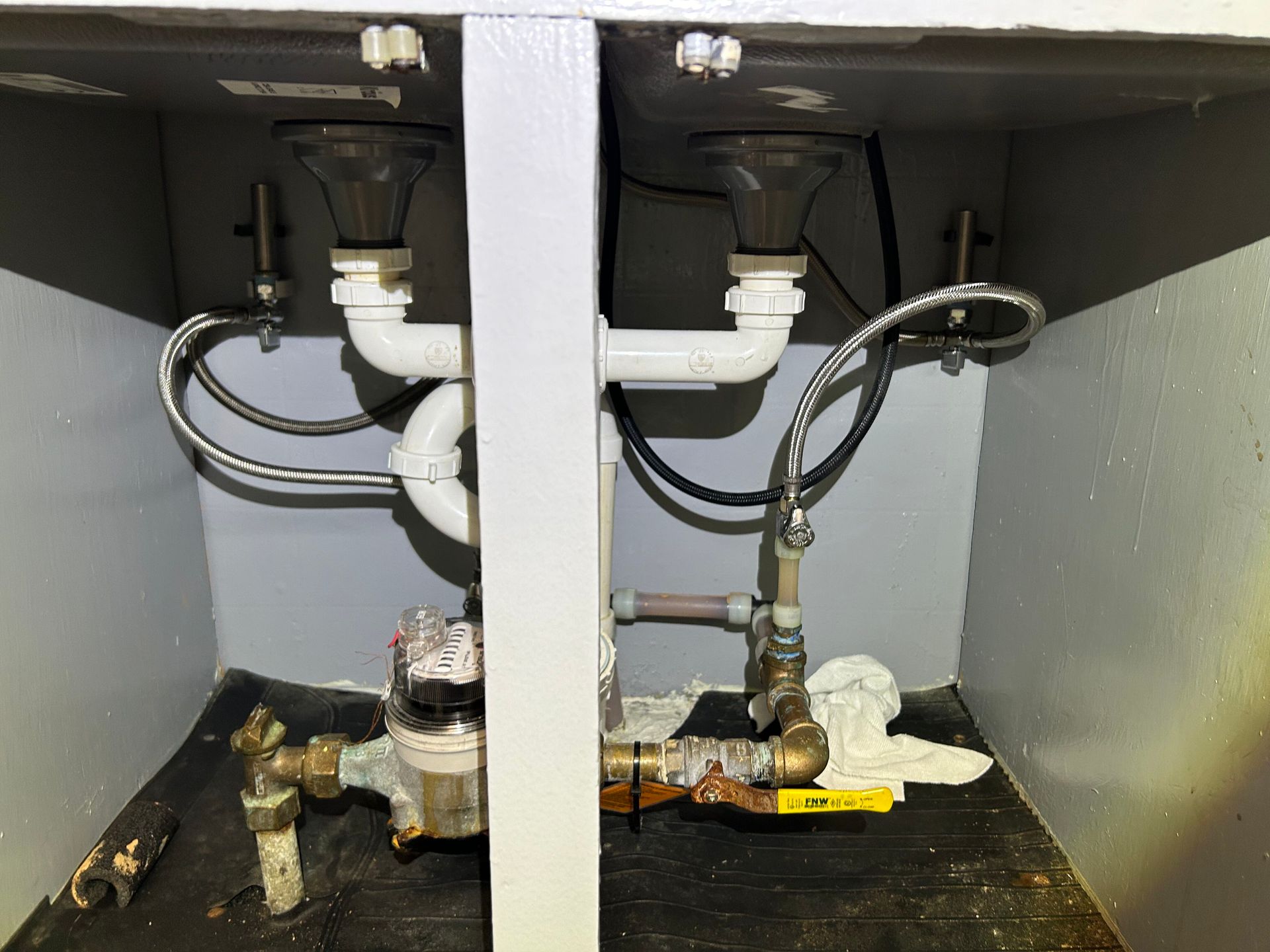 A kitchen sink with a yellow gas valve underneath it