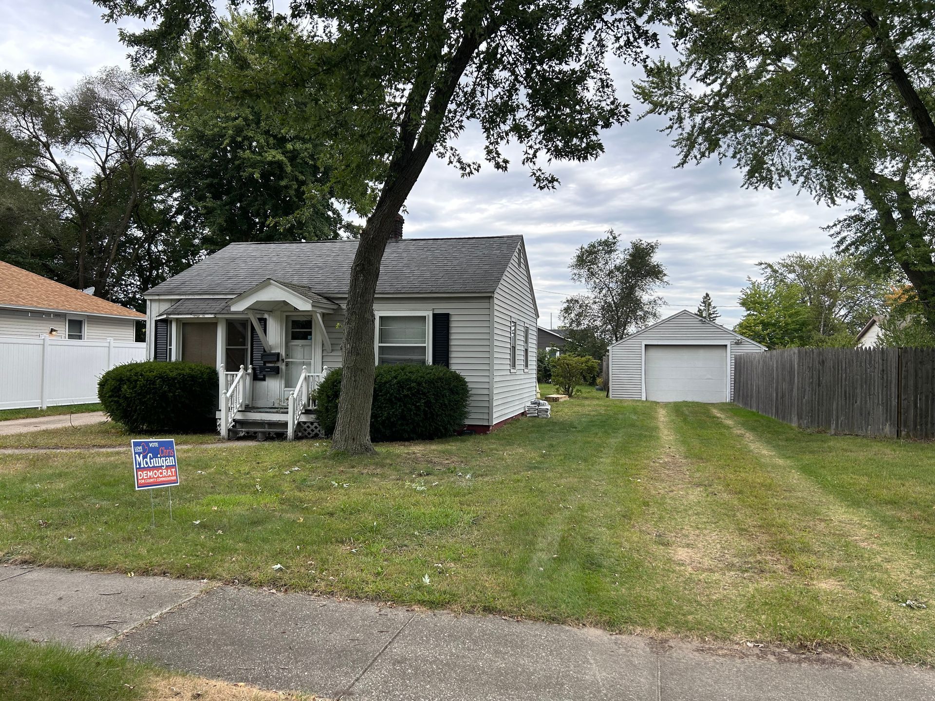 A small white house with a for sale sign in front of it.