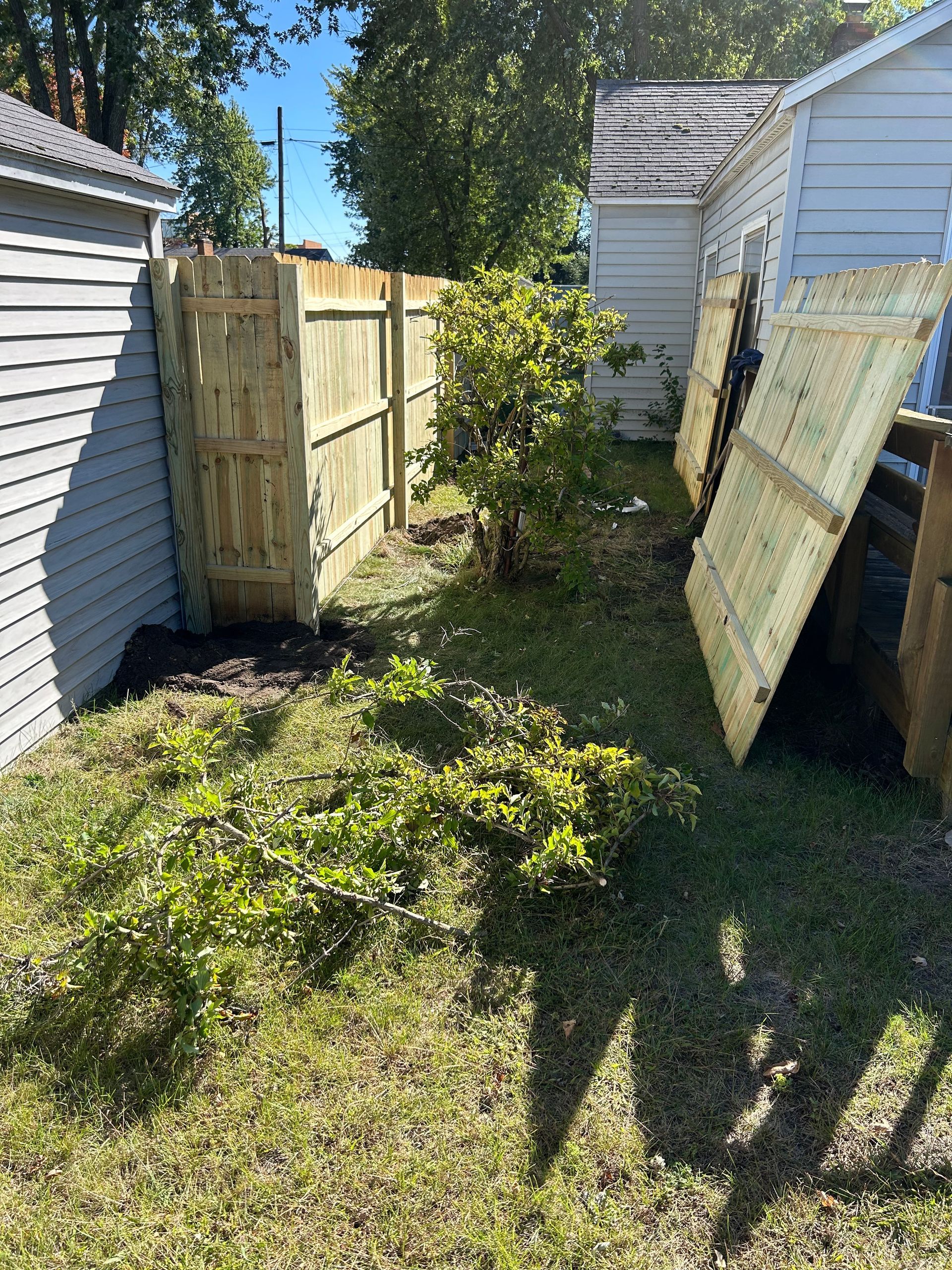 A wooden fence is in the backyard of a house.