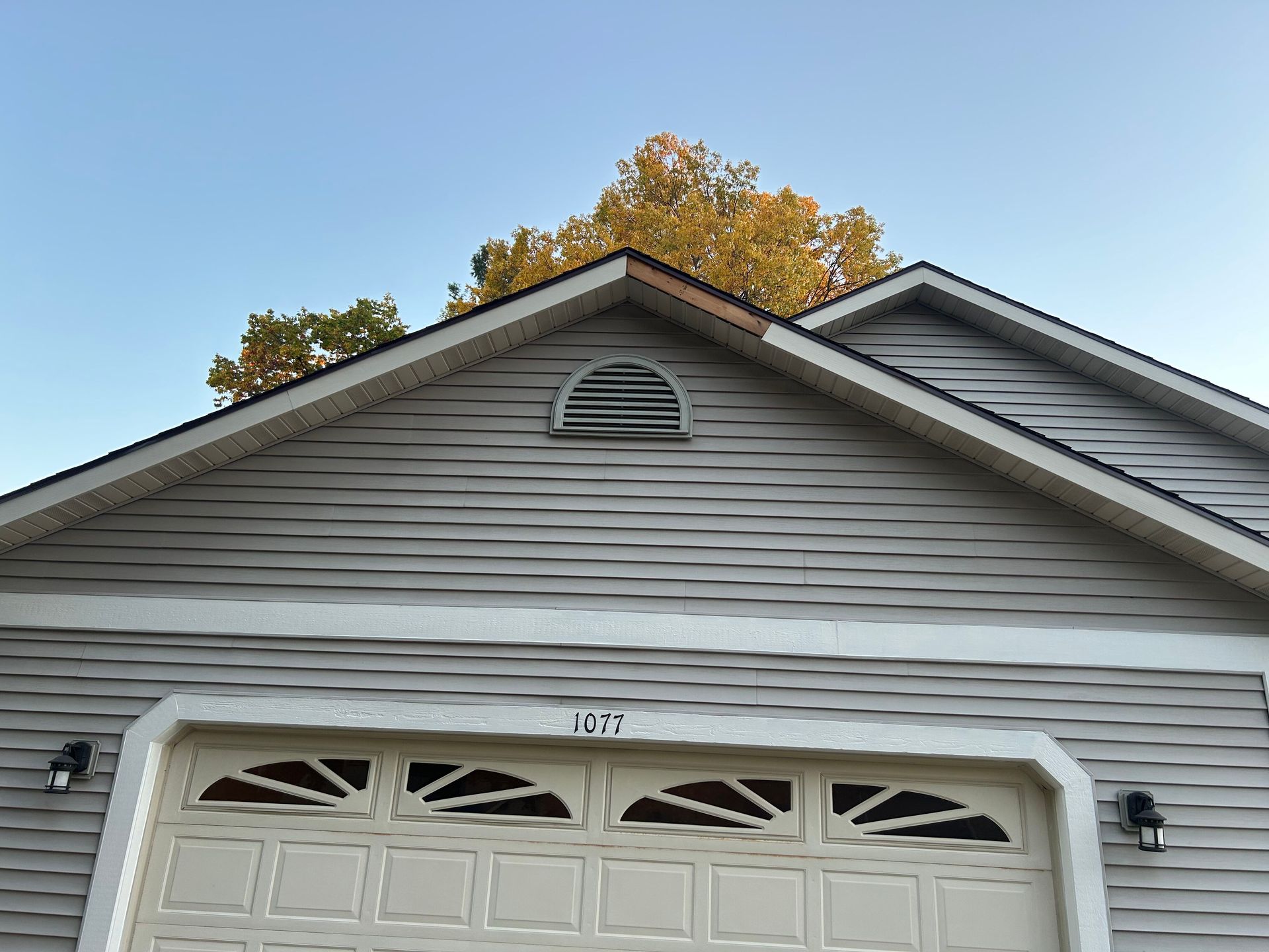 A house with a garage door and a tree in the background