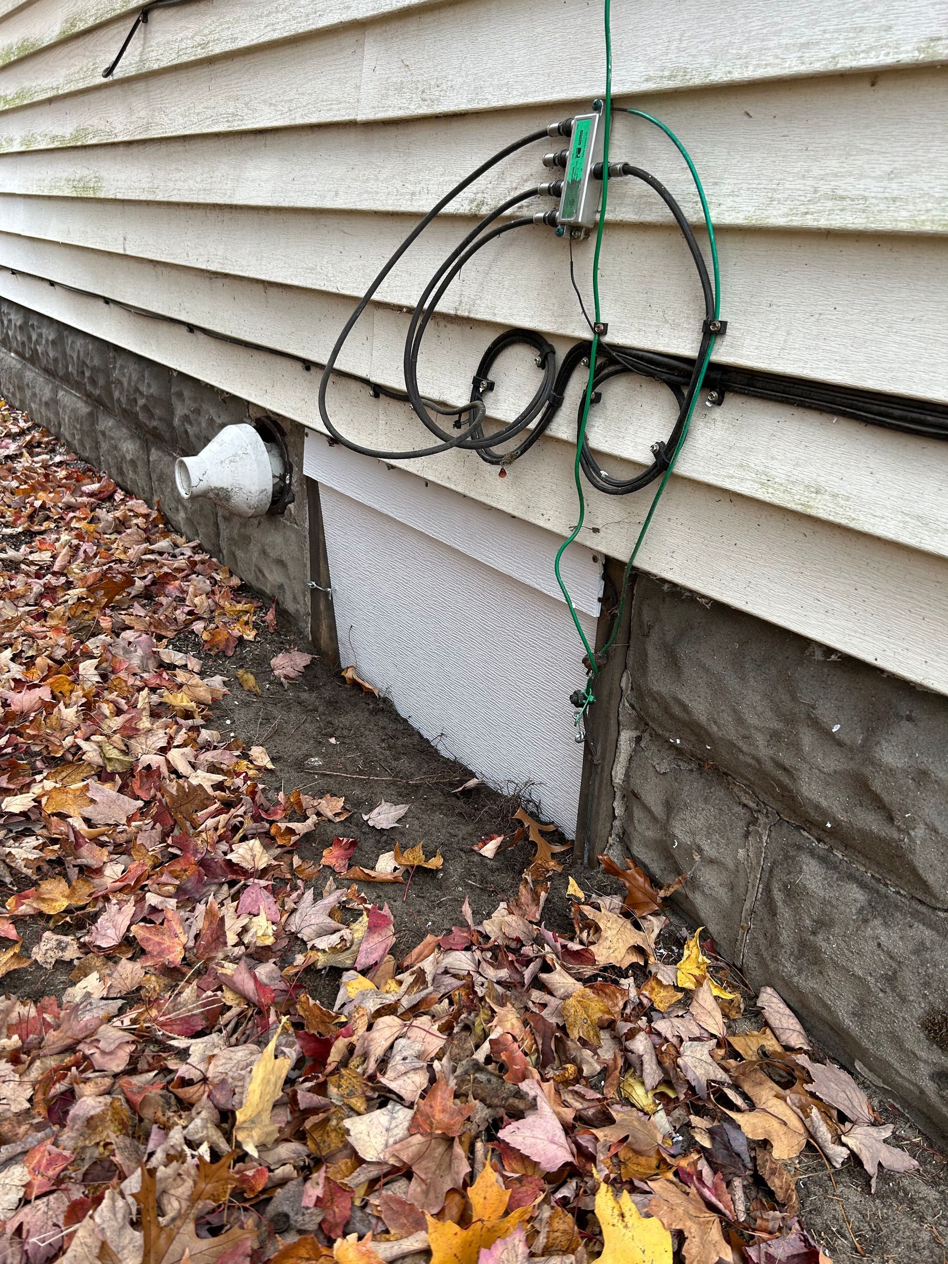 A bunch of wires are hanging from the side of a house.