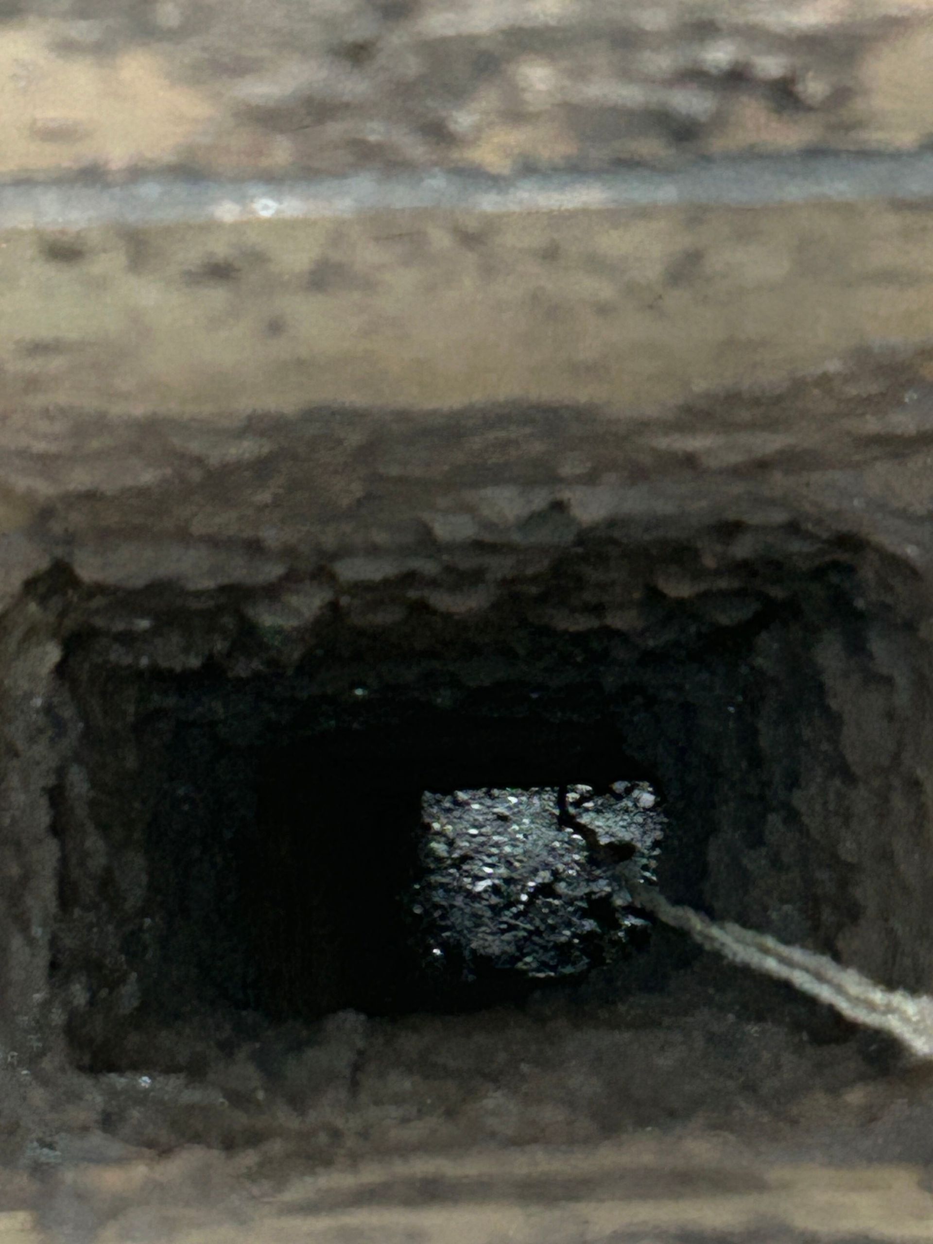 A close up of a hole in a wall with a rope coming out of it.