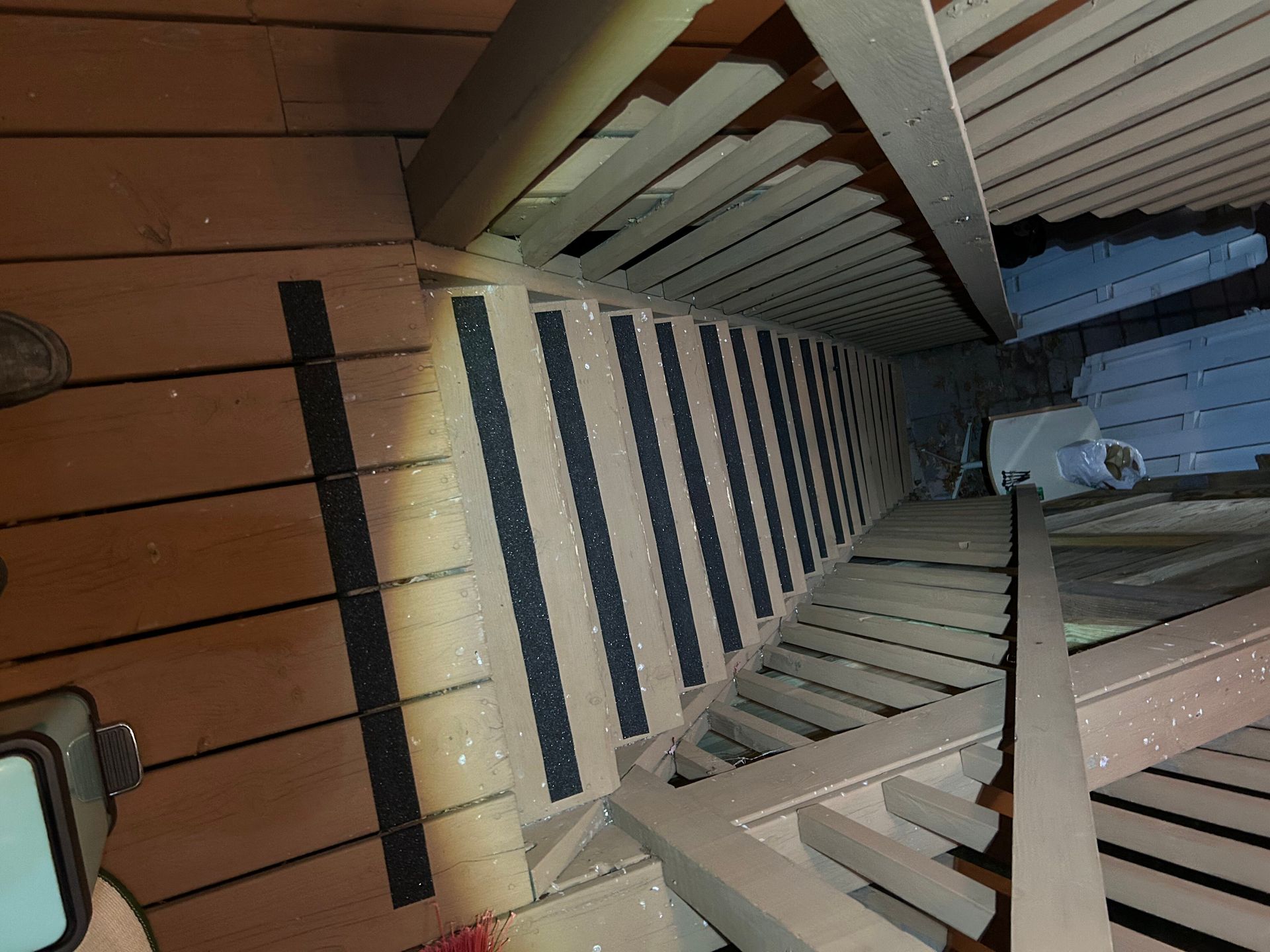 A person is standing on a wooden deck next to a set of stairs.