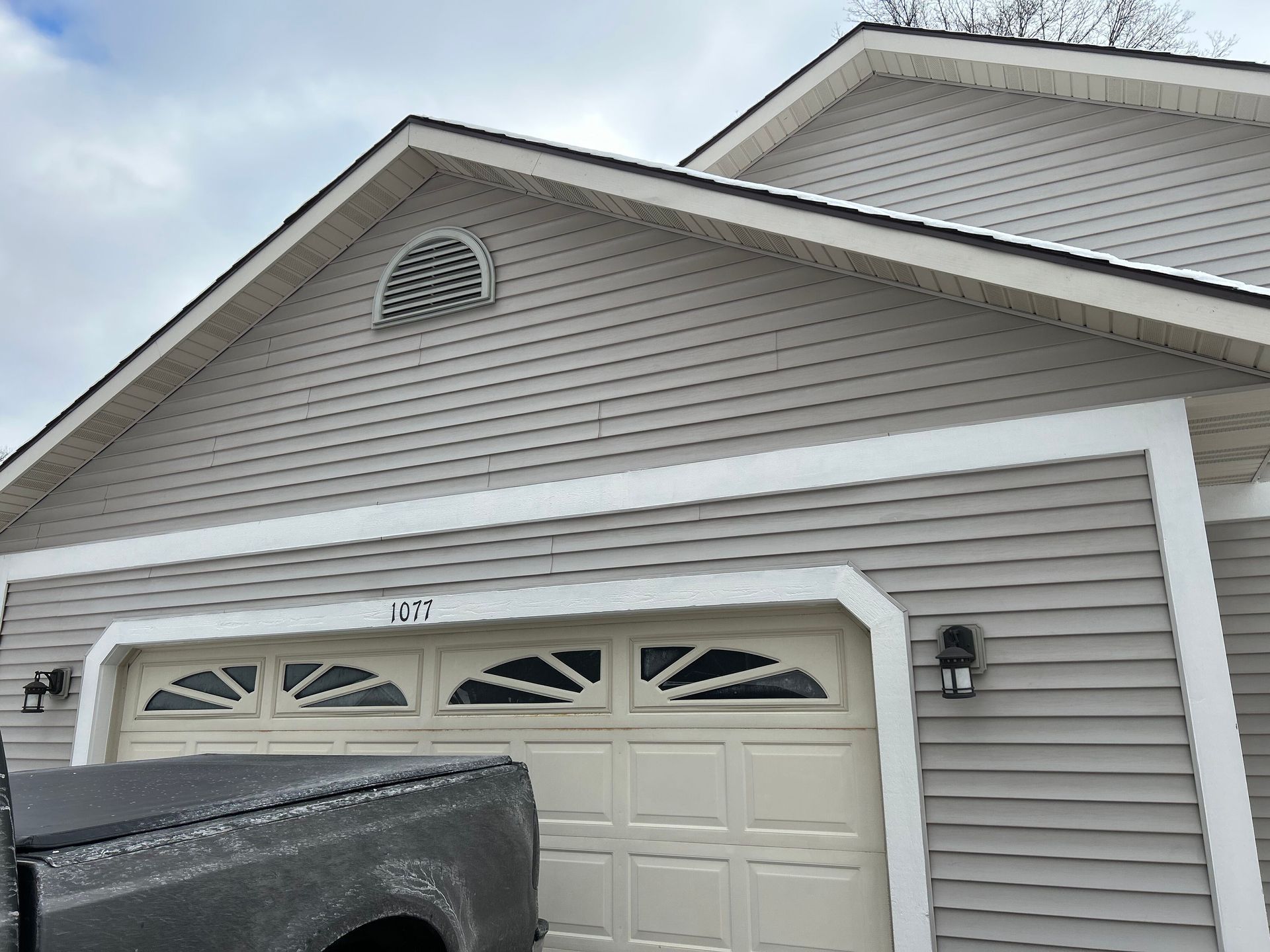 A truck is parked in front of a house with a garage door.