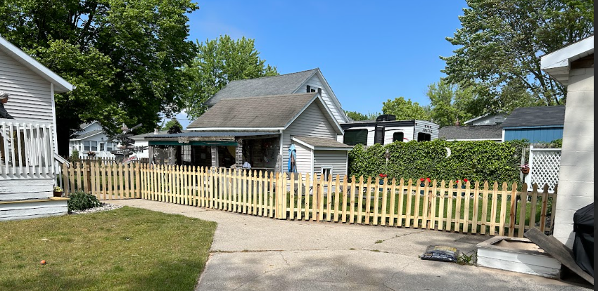 A wooden picket fence is in front of a house.