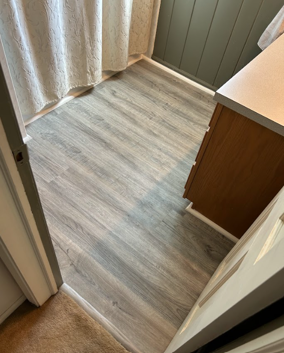 A bathroom with a wooden floor and a shower curtain.