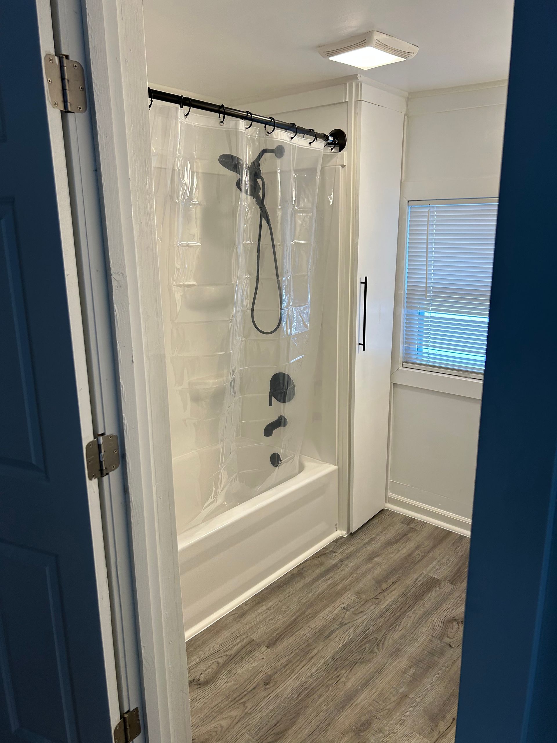 A bathroom with a tub , shower , and window.