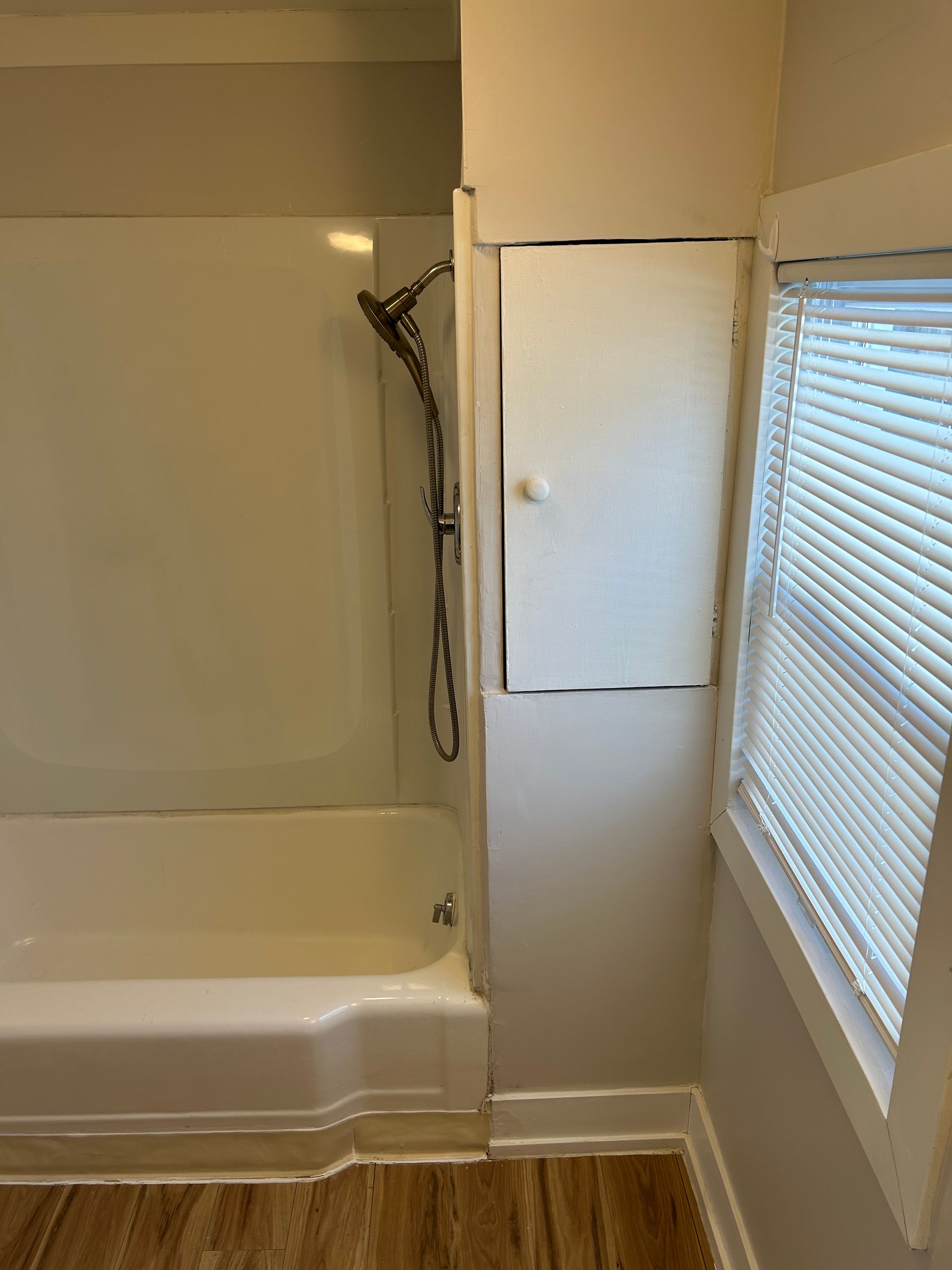 A bathroom with a bathtub and a window with blinds.