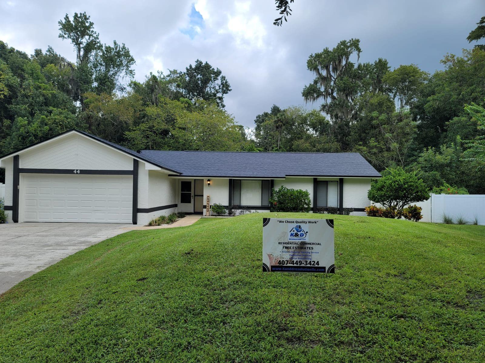 A white house with a blue roof and a sign in front of it