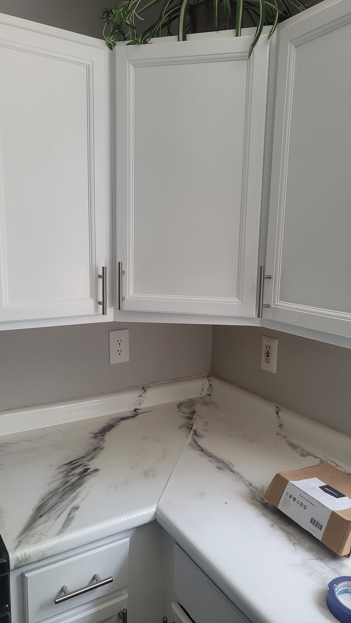 A kitchen with white cabinets and marble counter tops.