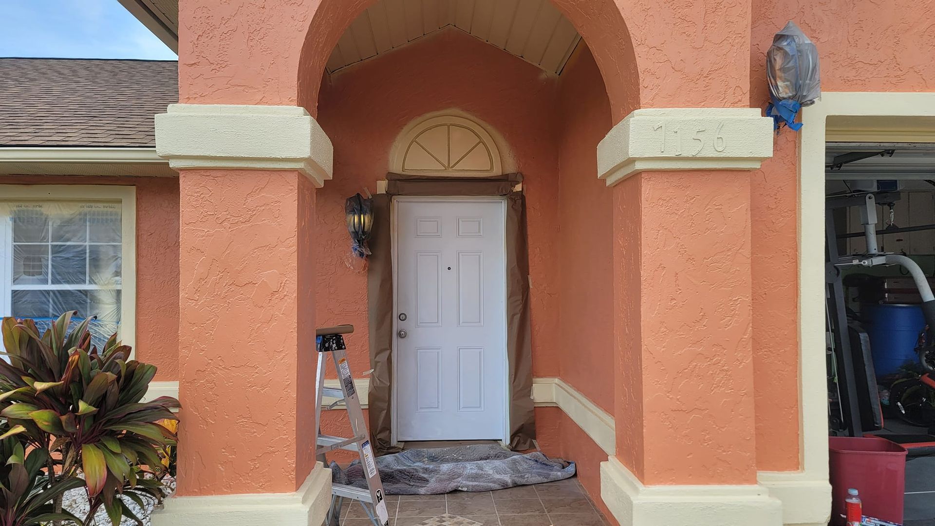 A house with a white door and a ladder in front of it.