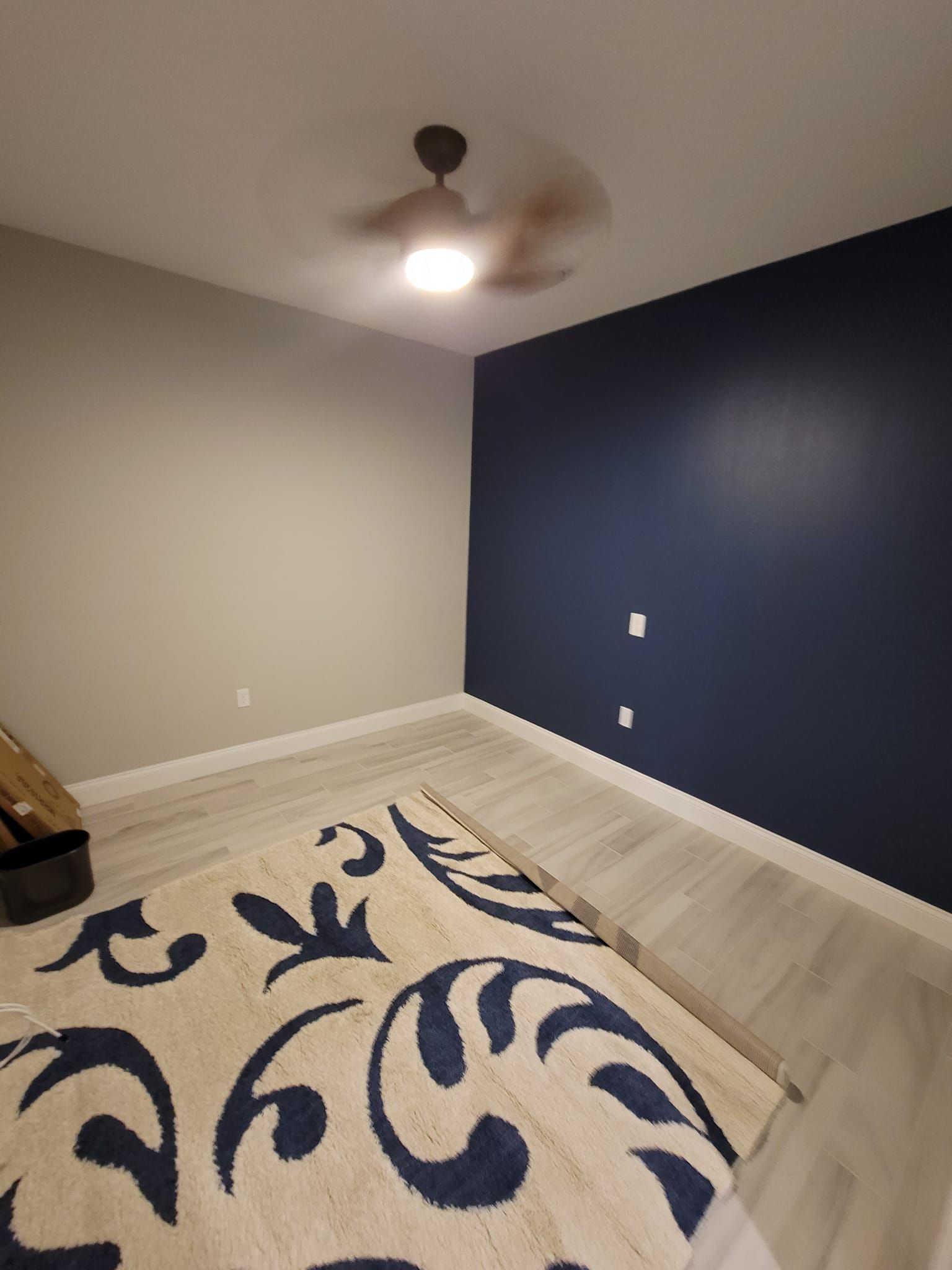 A bedroom with a rug and a ceiling fan.
