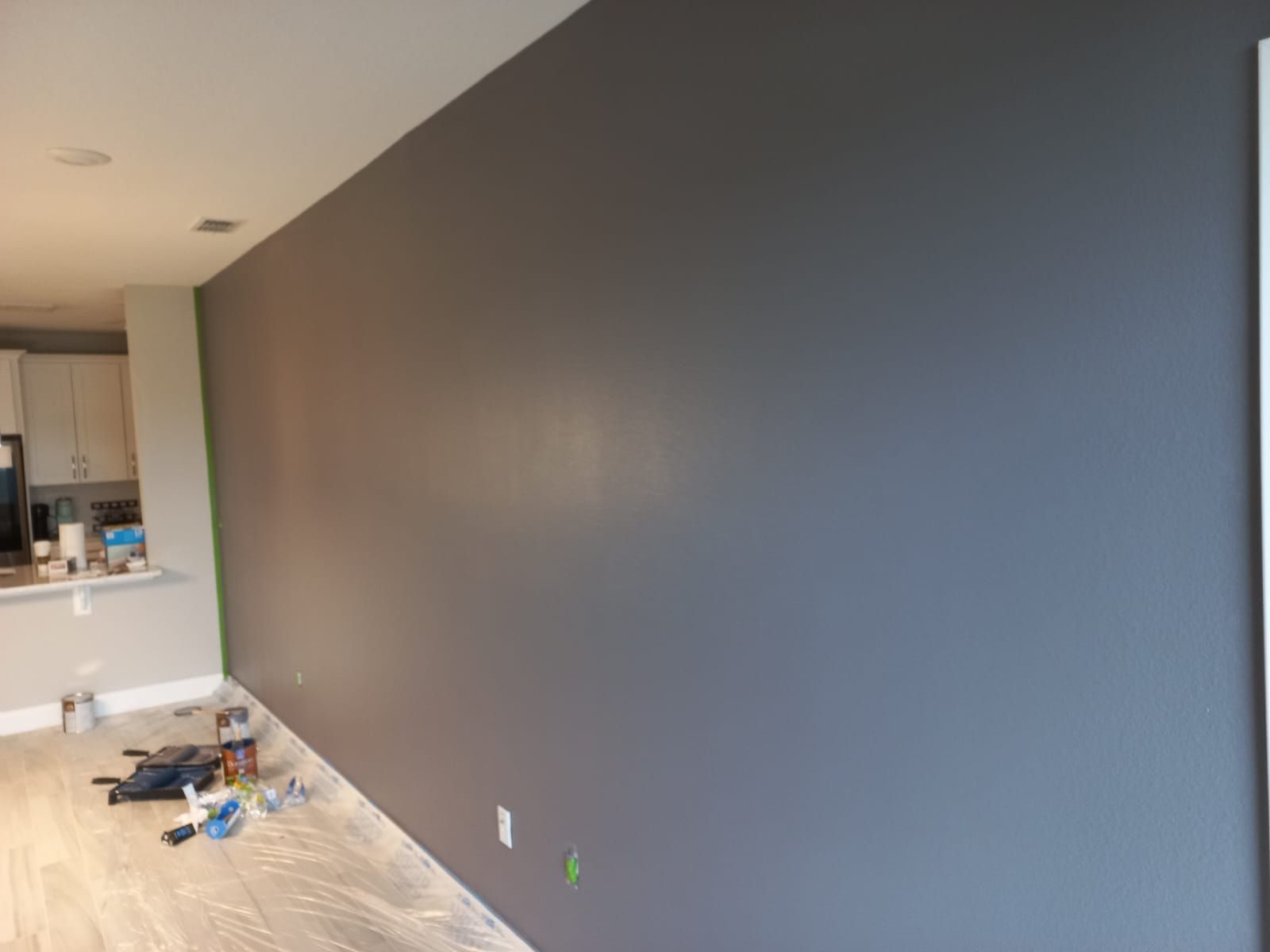 A gray wall is being painted in a living room.