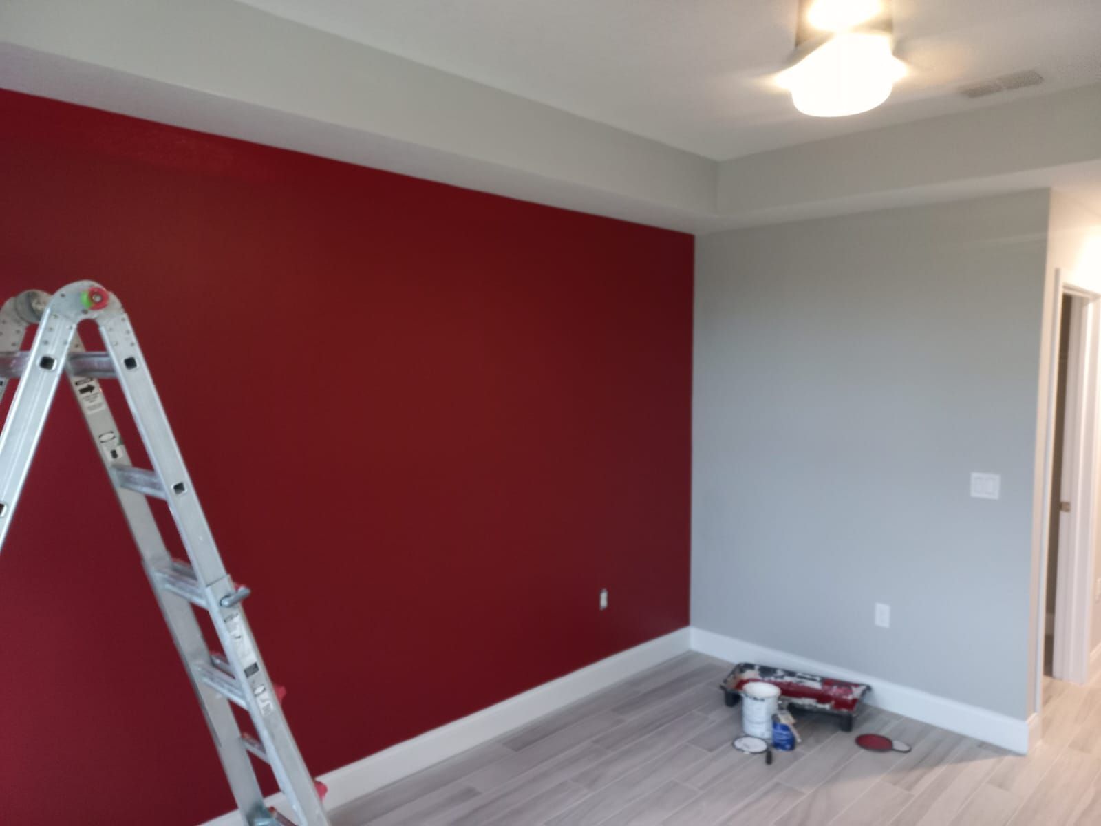 An empty room with a red wall and a ladder