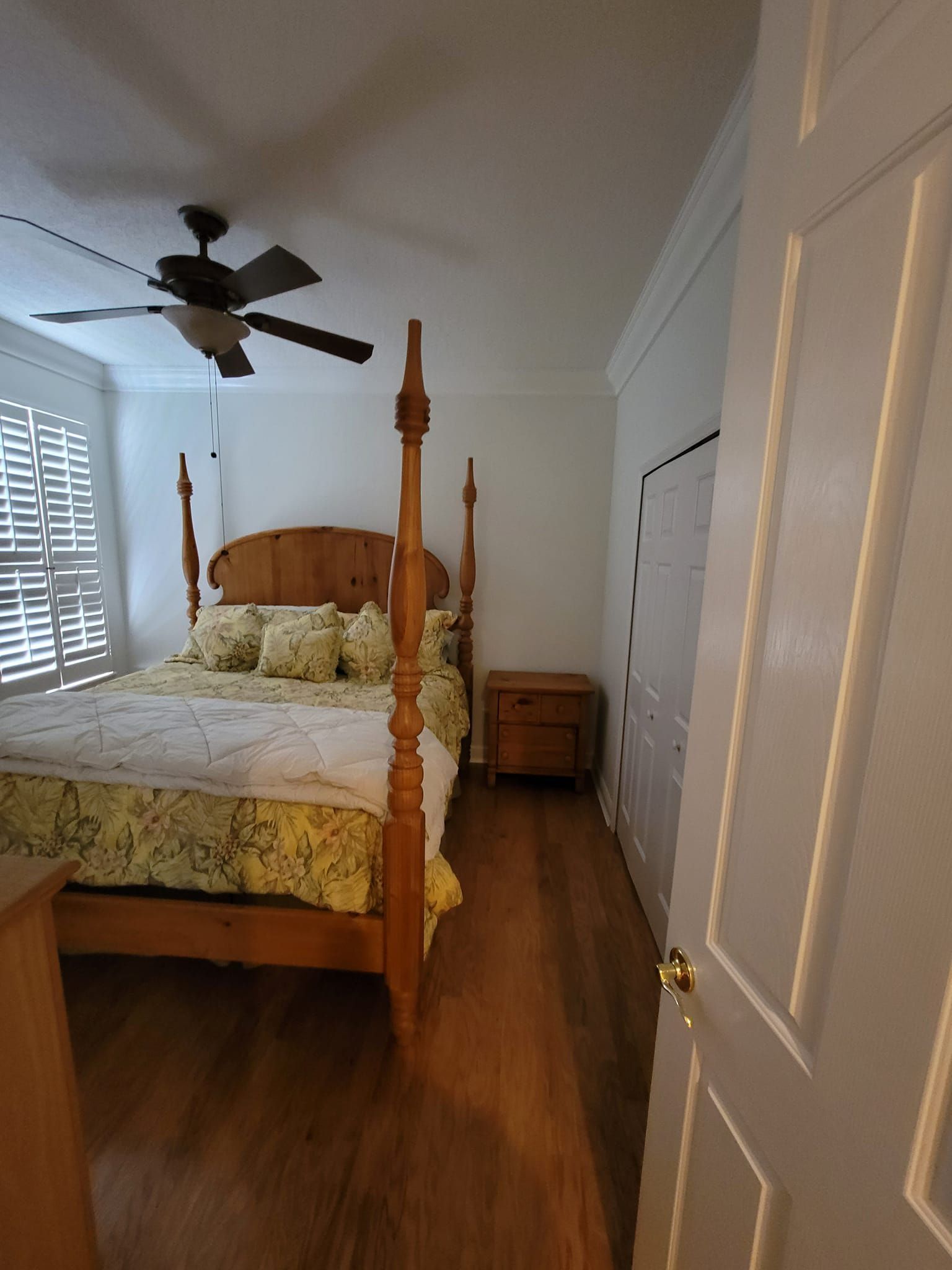 A bedroom with a four poster bed and a ceiling fan.