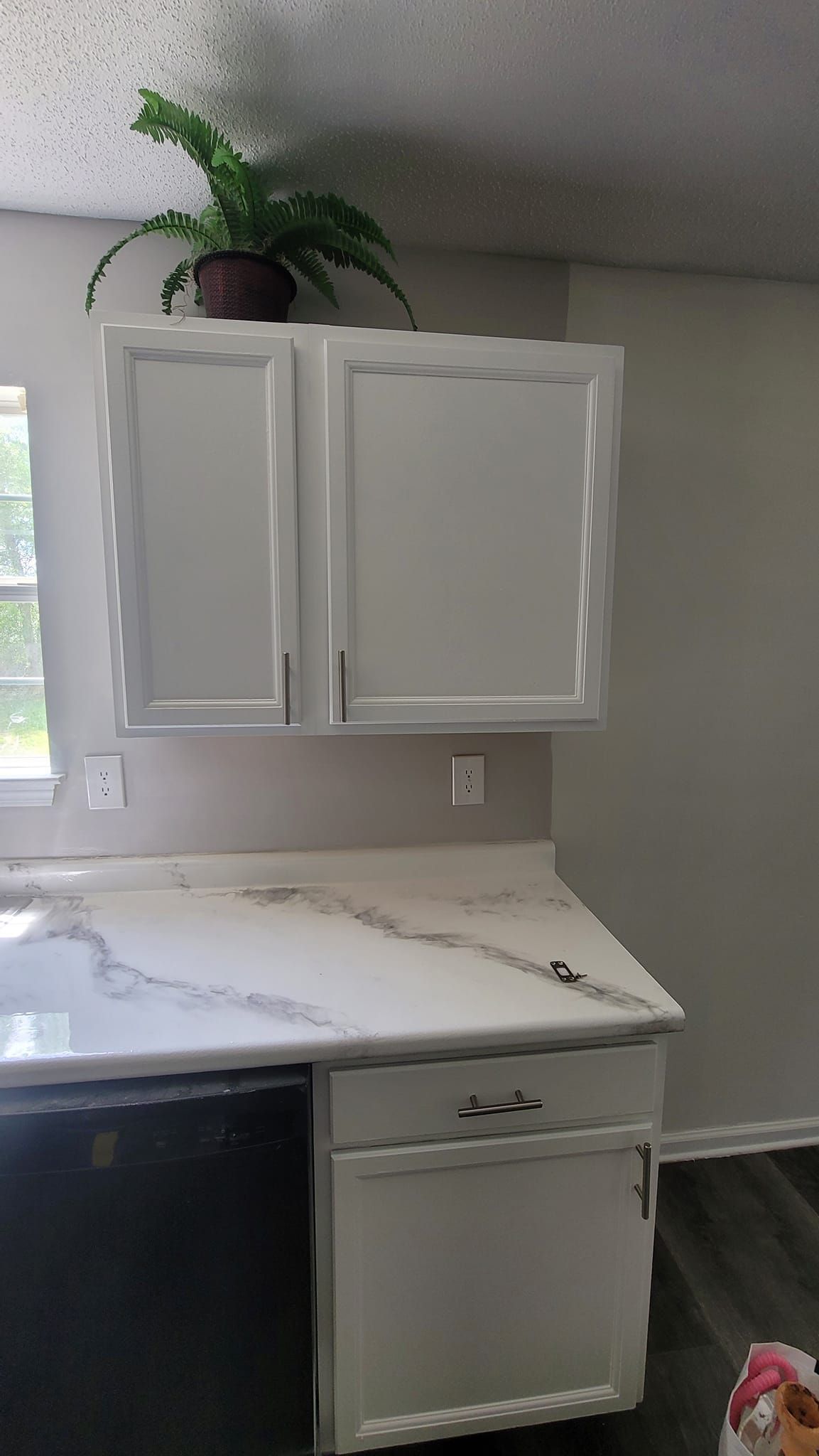 A kitchen with white cabinets , a sink , and a dishwasher.