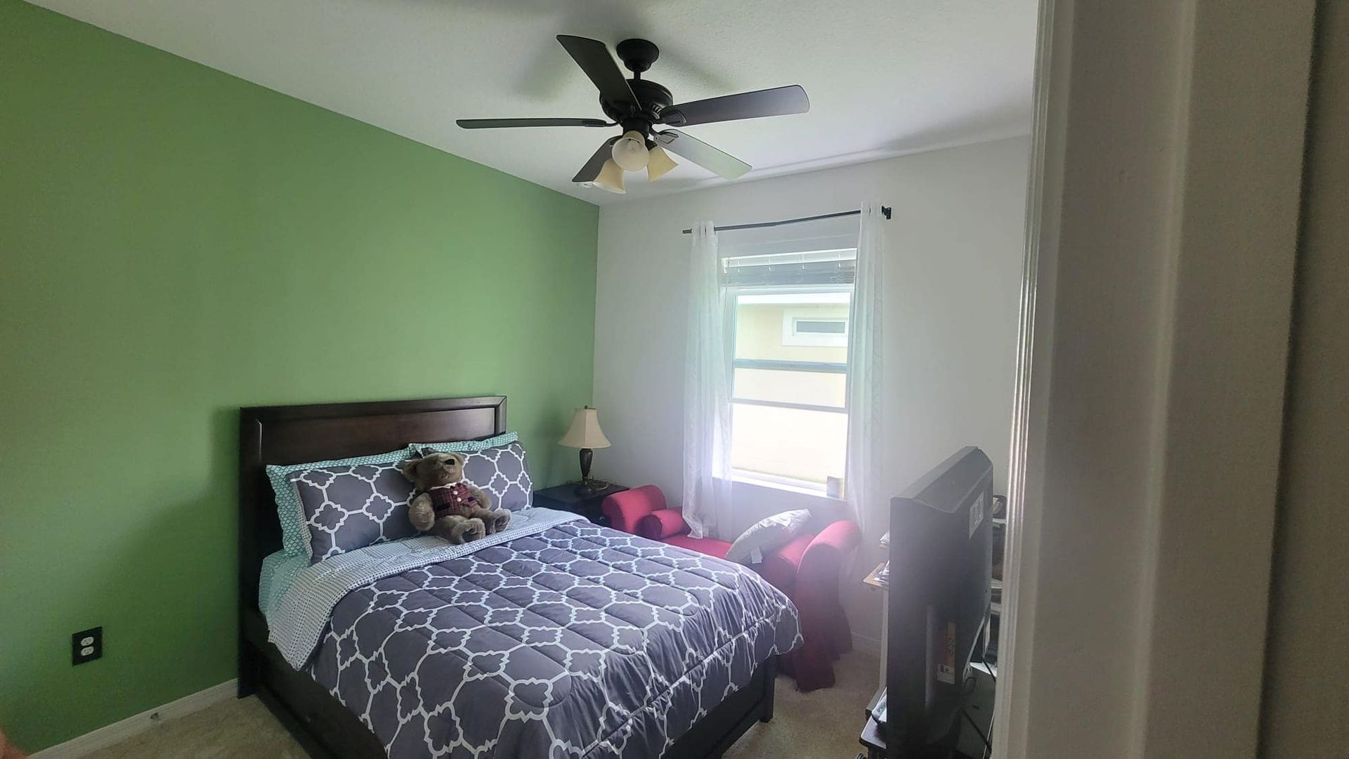 A bedroom with a bed and a ceiling fan.