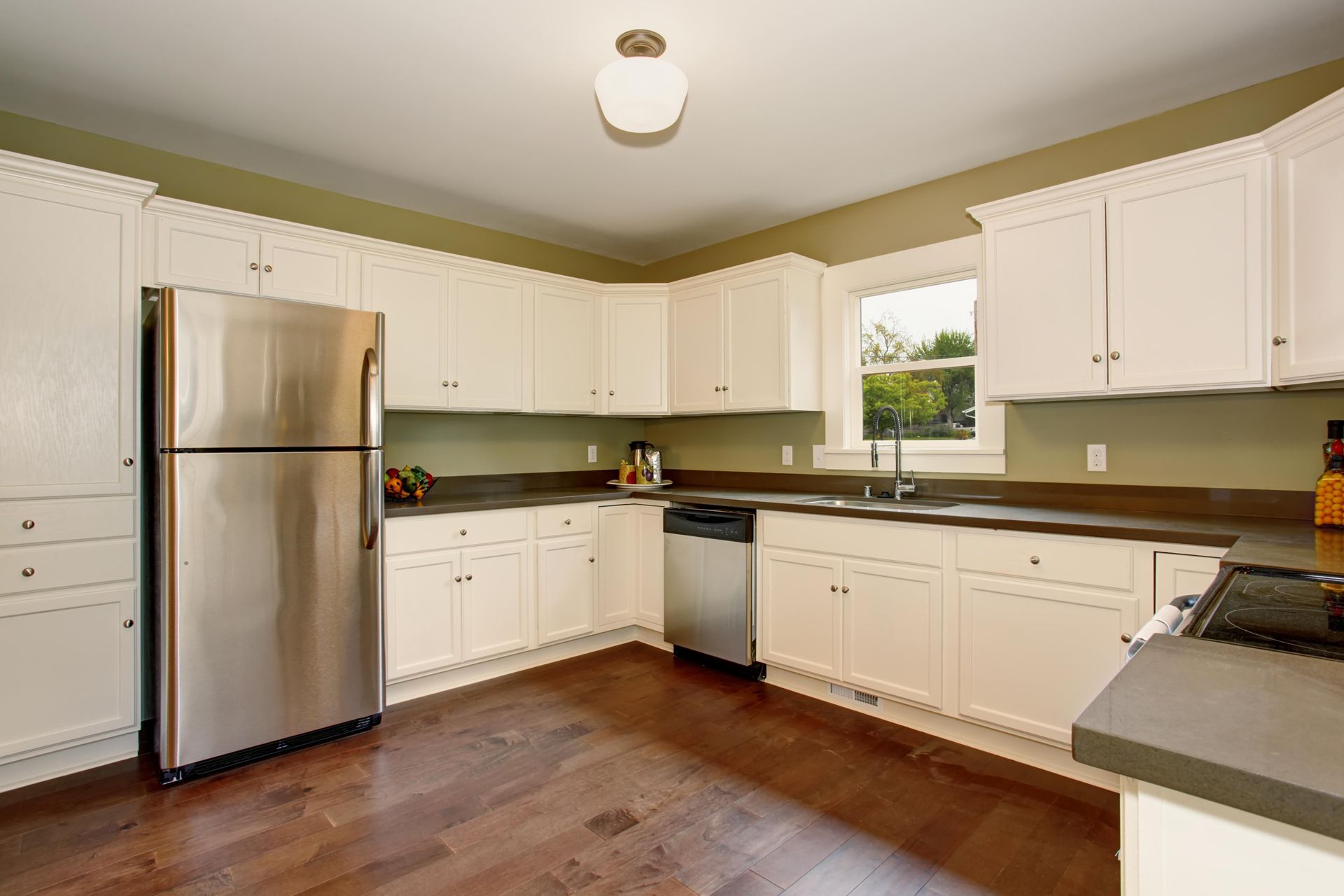 A kitchen with white cabinets, stainless steel appliances, and hardwood floors.