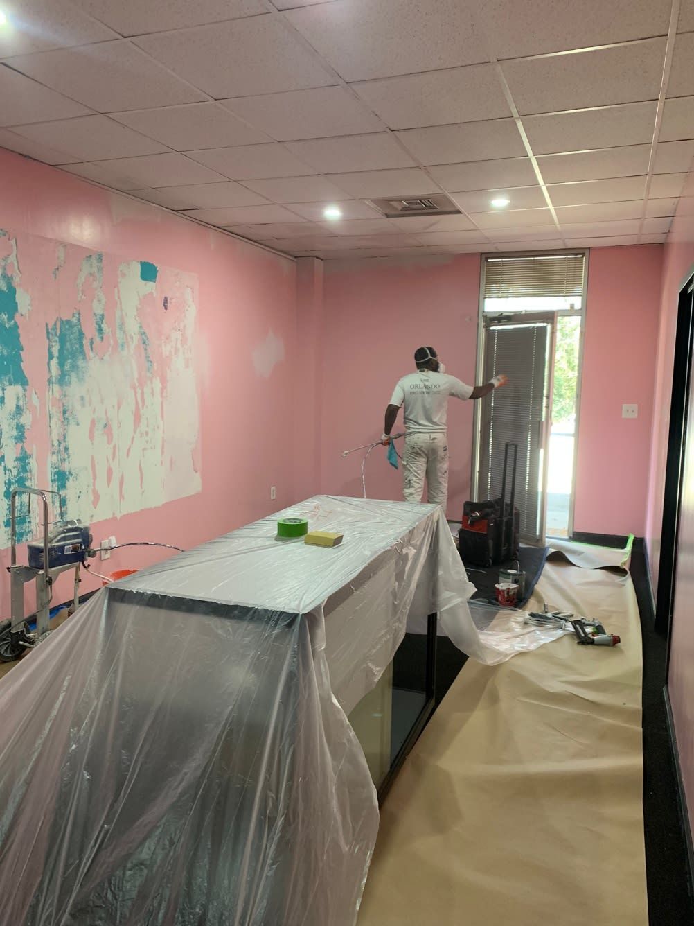 A man is painting a room with pink walls.