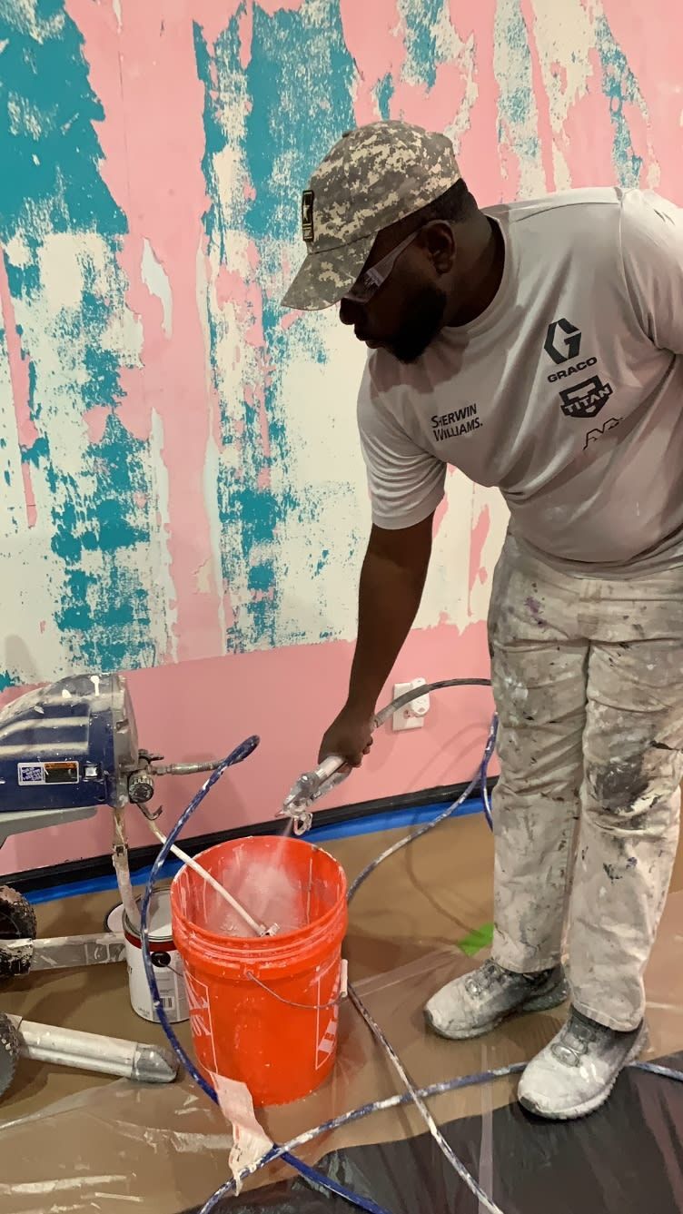 A man is painting a wall with a sprayer.