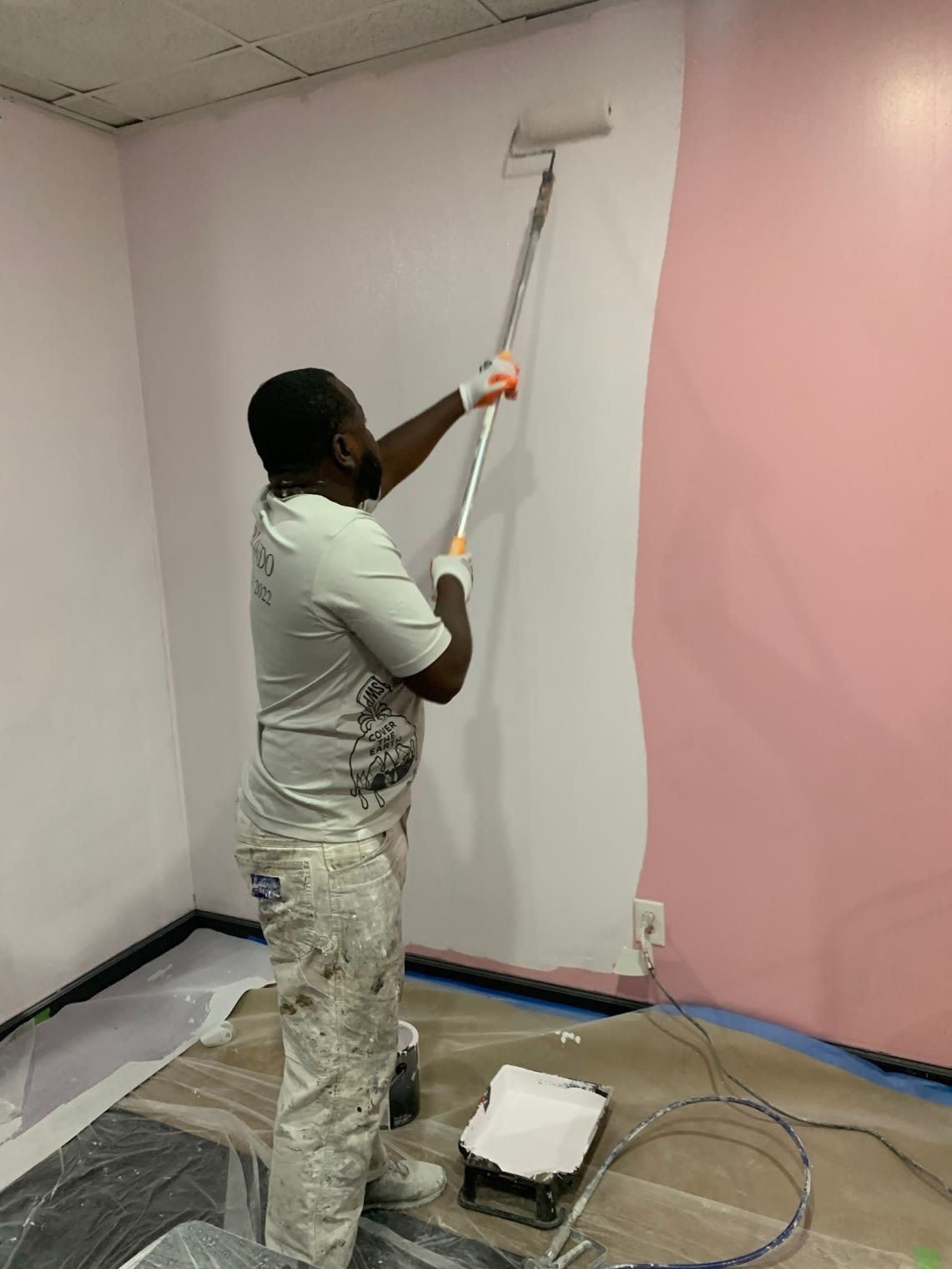 A man is painting a wall with a paint roller.