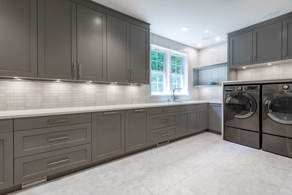 A laundry room with gray cabinets, a washer and dryer, and a sink.