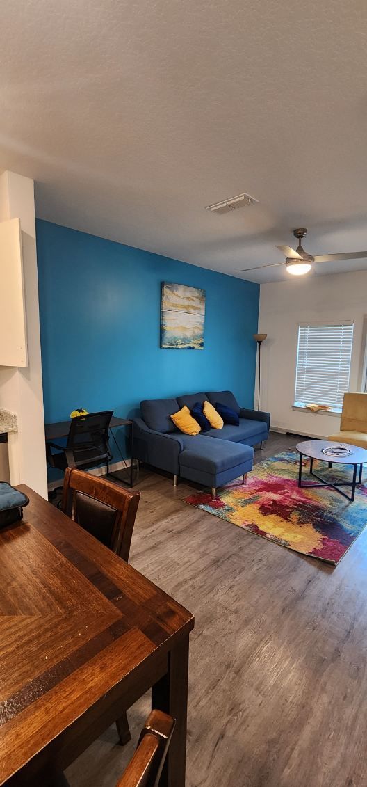 A living room with a blue couch and a wooden table.