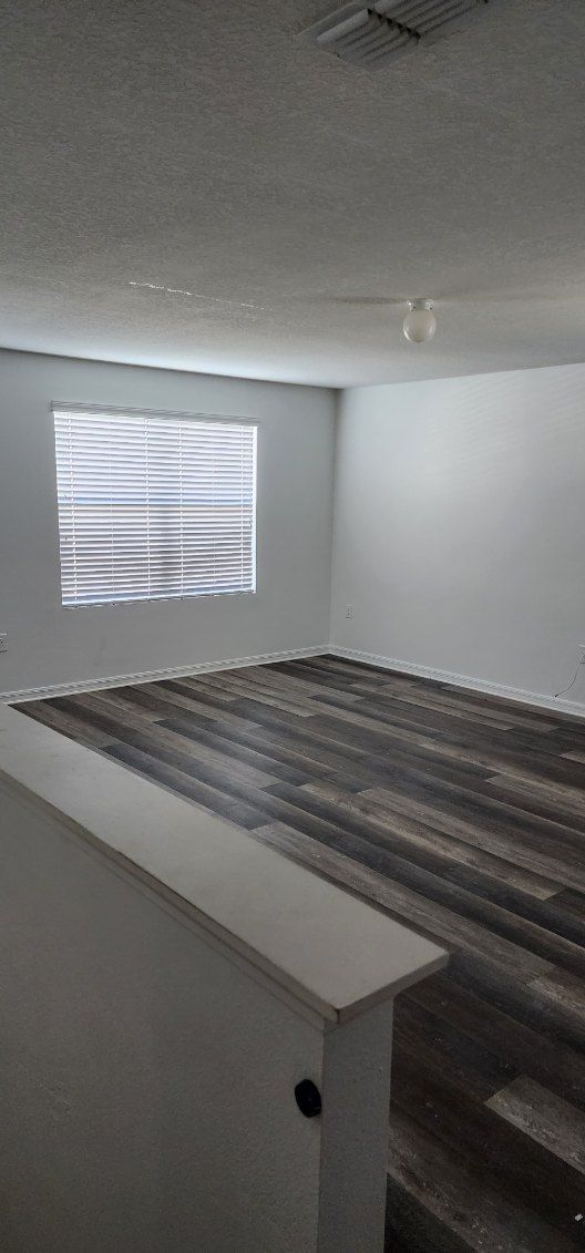 An empty living room with hardwood floors and a window.