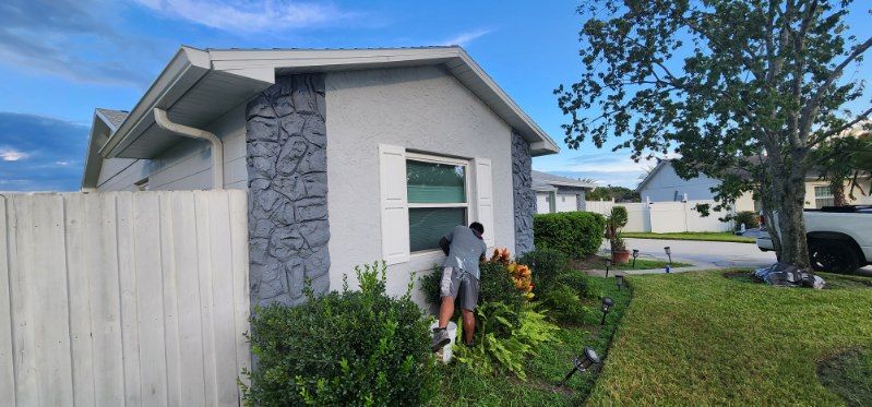 A man is standing in front of a house with a white fence.