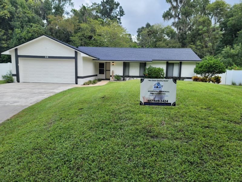 A white house with a blue roof and a sign in front of it.