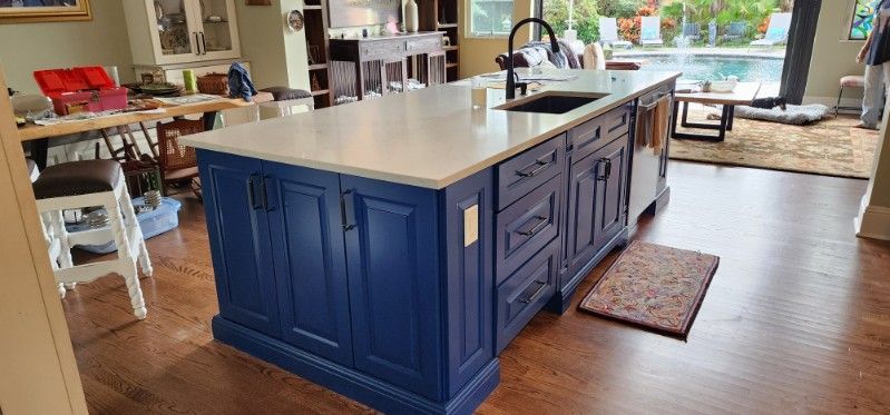 A kitchen with blue cabinets and a large island with a sink.
