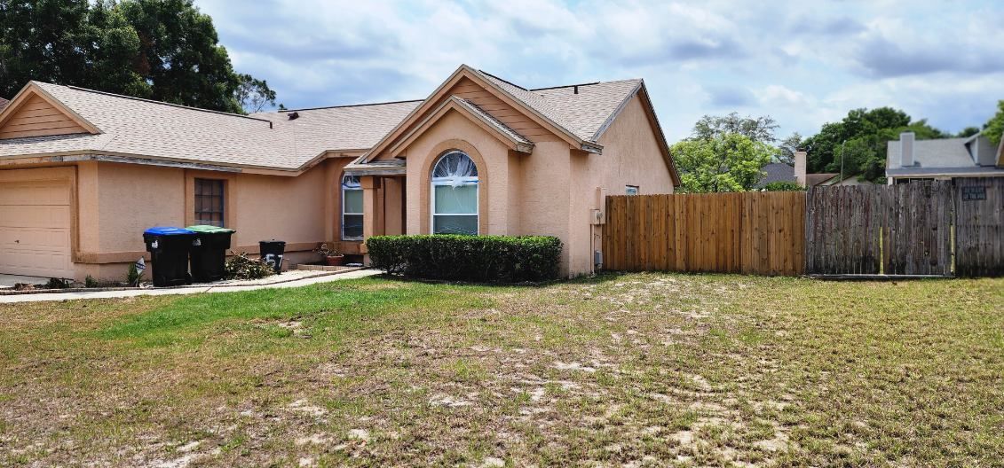 A house with a fence and a lot of grass in front of it.