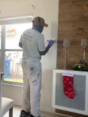 A man is painting a wall in a living room.