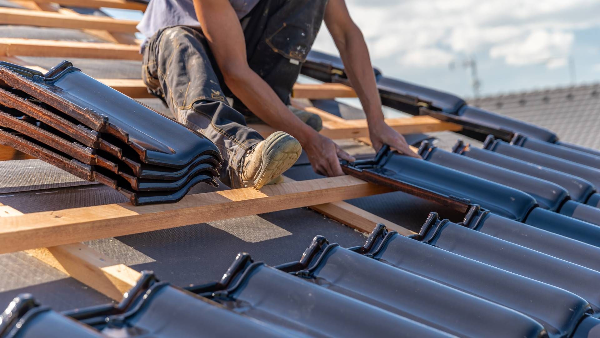 A man is laying tiles on a roof.