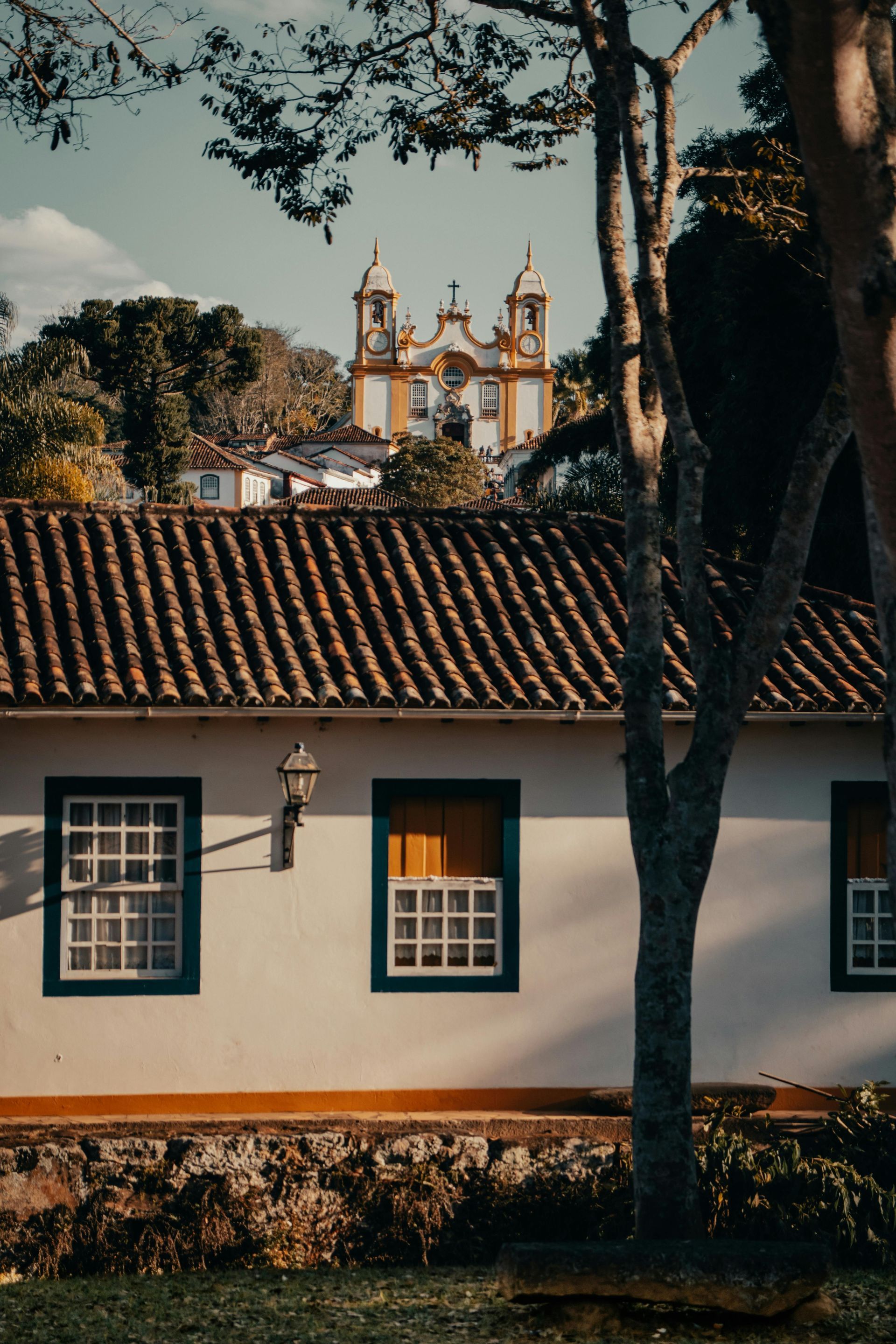 A white house with a tiled roof and a church in the background