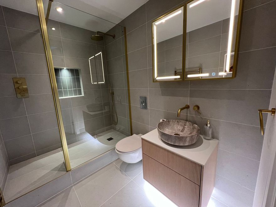 A bathroom with a sink , toilet , shower and mirrors.