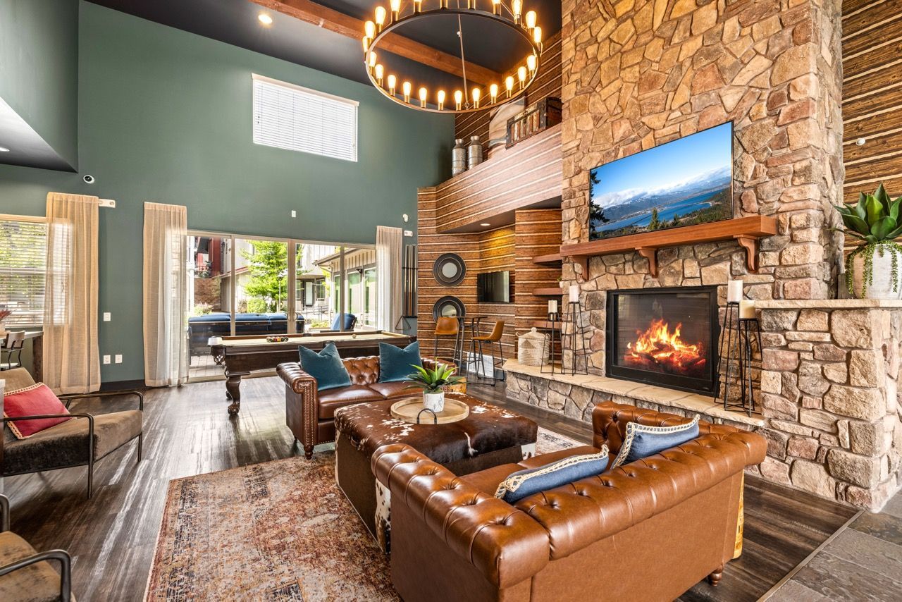 Modern community lounge with a stone fireplace, mounted TV, and pool table.