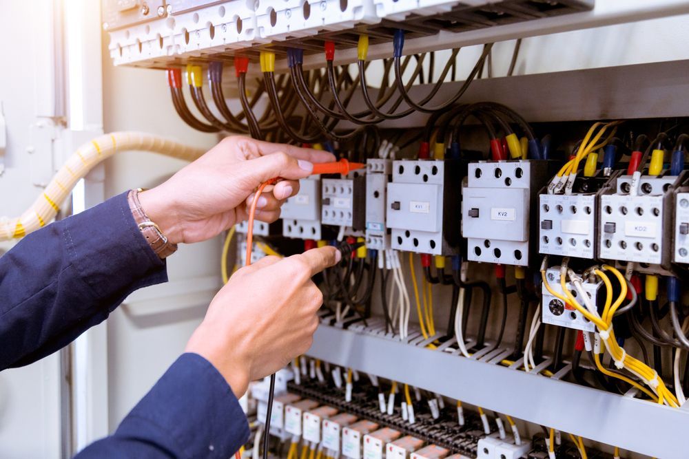 A man is working on an electrical panel with a screwdriver.