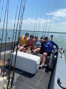 A group of people are sitting on a boat with fishing rods.