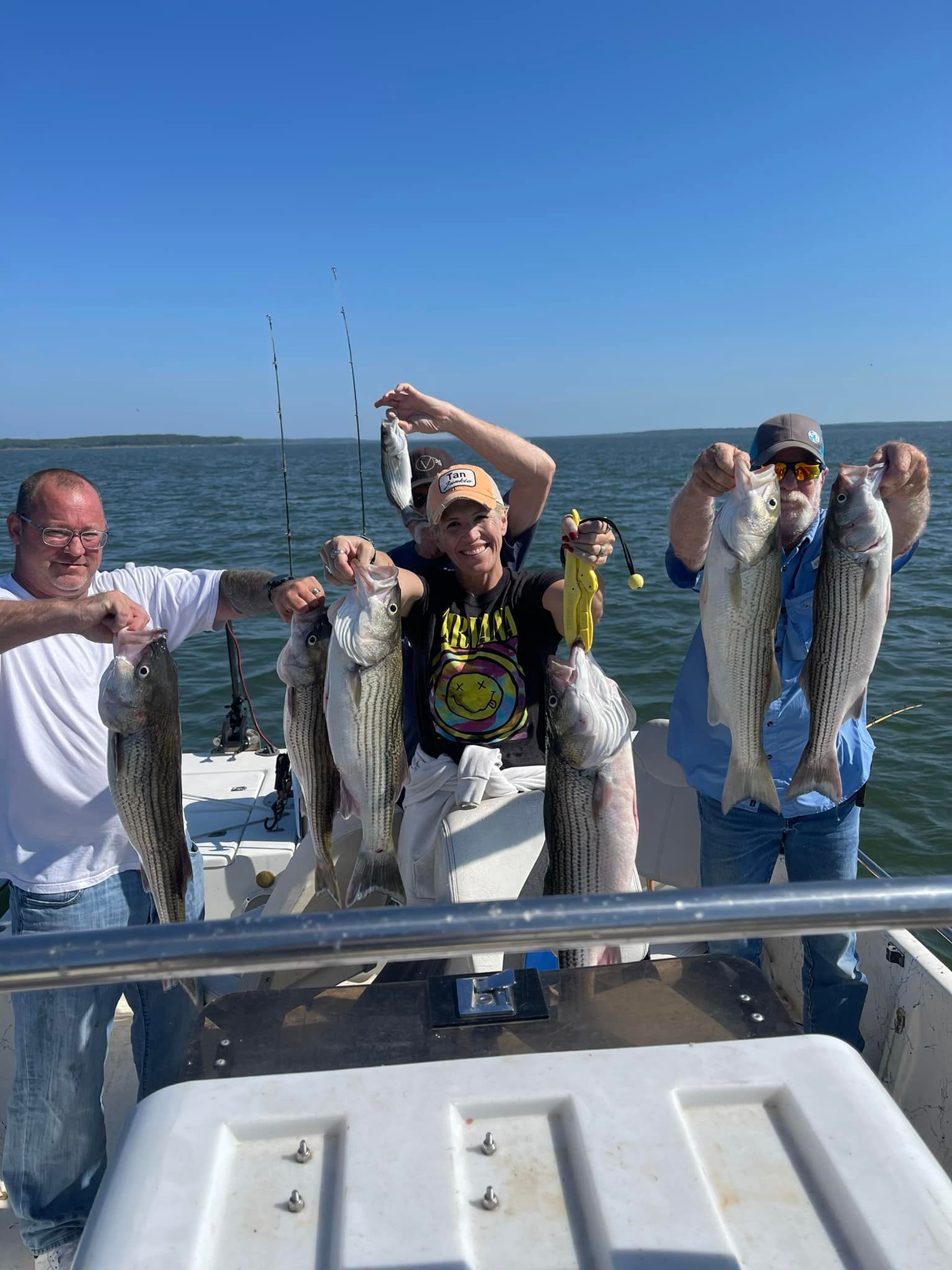 A group of men are standing on a boat holding fish.