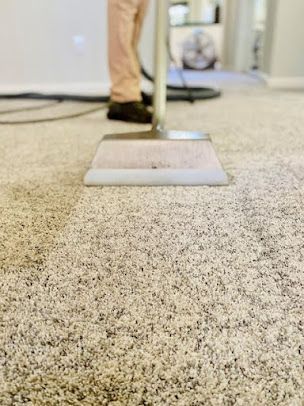 A person is cleaning a carpet with a vacuum cleaner.