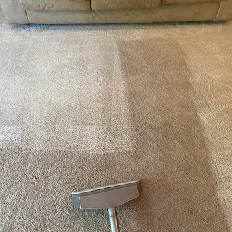 A vacuum cleaner is cleaning a carpet in a living room.