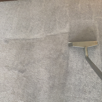 A vacuum cleaner is cleaning a carpet in a living room.