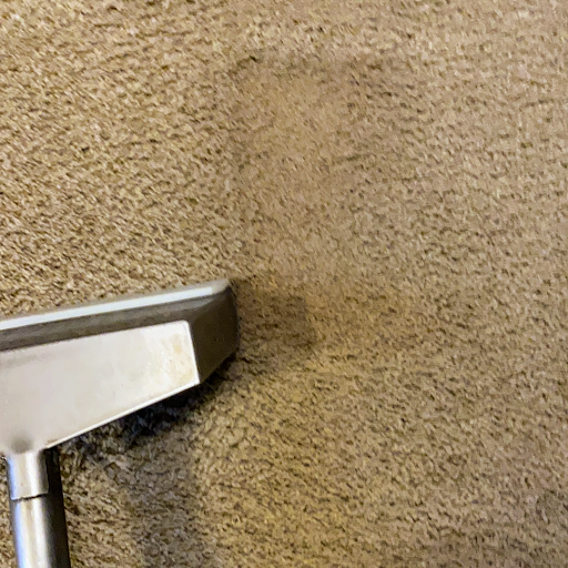 A vacuum cleaner is being used to clean a carpet.