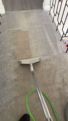 A person is cleaning a carpet with a vacuum cleaner.