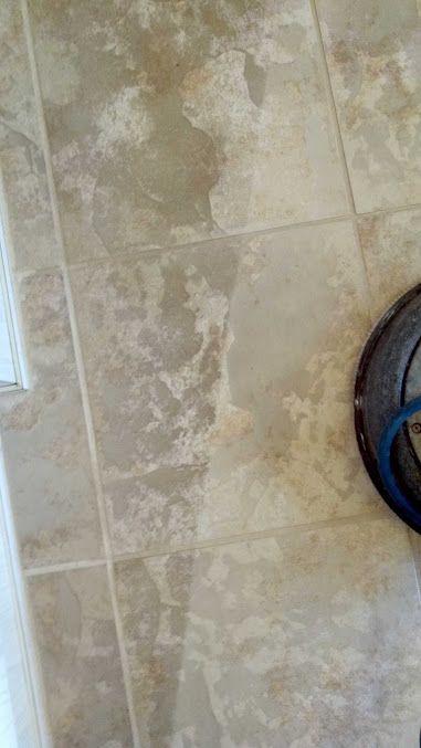 A close up of a tile floor with a vacuum cleaner on it.