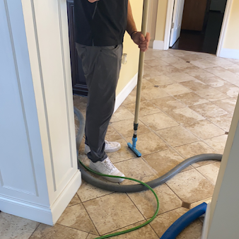 A man is standing next to a vacuum cleaner on a tiled floor.