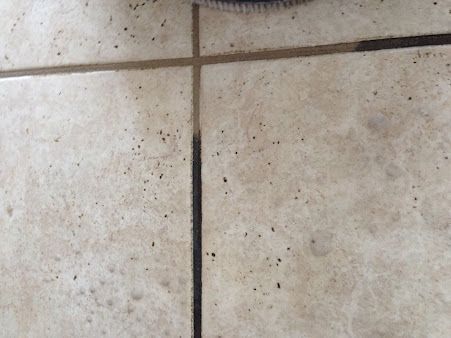 A close up of a tile floor with a brush on it.